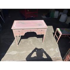 a pink desk and chair sitting on top of a cement floor next to each other