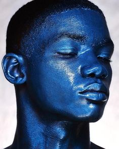 a young man with blue paint on his face and chest is posing for the camera