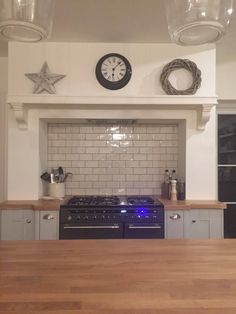 a kitchen with an oven, stove and counter top in the center is lit up by three hanging lights