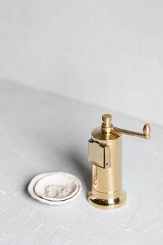 a gold colored soap dispenser next to a white plate on the floor