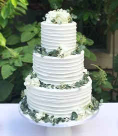 a three tiered cake with white flowers and greenery