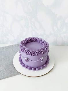 a purple cake sitting on top of a white plate next to a gray and white wall