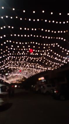 the lights are hanging from the ceiling in the parking lot as cars drive down the street