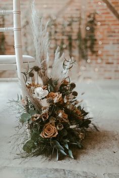 a bouquet of flowers sitting on top of a white chair next to a brick wall