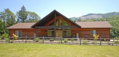 a large log cabin sits in the middle of a field