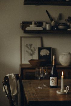 a bottle of wine sitting on top of a wooden table next to a lit candle