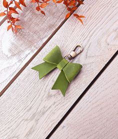 an origami bow keychain is sitting on a wooden table next to some leaves