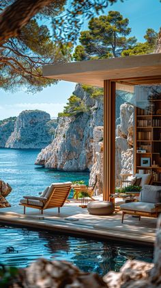 an outdoor living area overlooking the water and rocky coastline with chairs, bookshelves, and bookcases