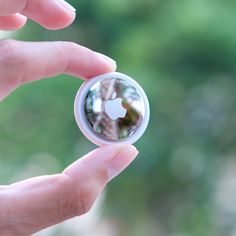 a person holding an apple logo in their left hand and looking at it through the lens