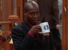 a man is holding a coffee mug in his right hand and looking at the camera