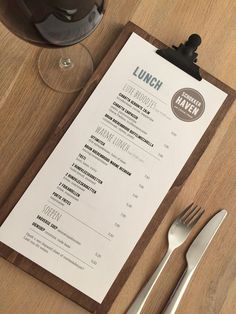 a menu sitting on top of a wooden table next to a glass of wine