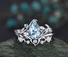 a blue topazte and diamond ring sits on a green rock with diamonds around it