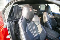 the interior of a sports car with black leather and red stitching on the seats