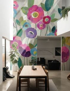 a dining room table and chairs in front of a wall with flowers painted on it