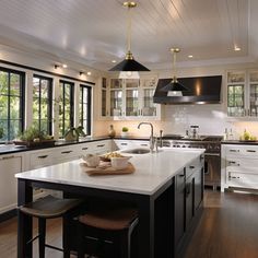 a large kitchen with white cabinets and black counter tops, along with an island in the middle