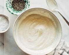 a white bowl filled with sauce next to two spoons on top of a table