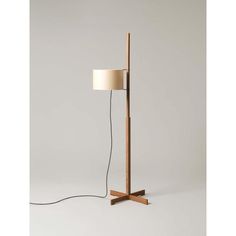 a wooden floor lamp with a white shade on the base and a black cord attached to it