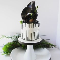 a black and white cake with greenery on top