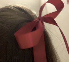 a close up of a person with a red ribbon on their head and hair tied in a ponytail