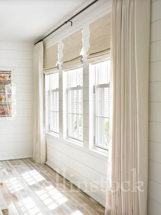 an empty room with white walls and wood flooring is pictured in this image, the light shines through the windows