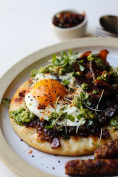 an egg is sitting on top of a flatbread with greens and other toppings