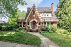 a small brick house with green grass and trees