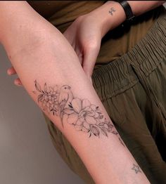 a woman's arm with flowers and birds on it, while she is holding her leg