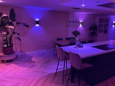 an empty kitchen with purple lighting in the middle and wooden flooring on the other side