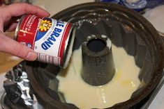 a person is pouring white liquid into a food processor to make something yellow and brown