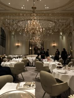 a dining room with chandeliers and tables set for formal dinner in the center