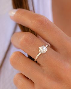 a woman wearing a pearl ring on her finger