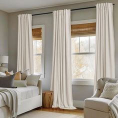 a living room filled with furniture and windows covered in white drapes on top of them