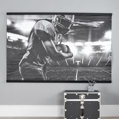 a black and white photo of a football player on the field with his helmet in front of him