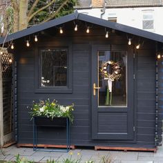 a black shed with flowers and lights on it