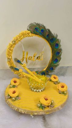 a yellow plate with peacock feathers on it and the name halda written in gold