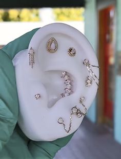 a person holding up a fake ear with many different jewelry pieces on top of it