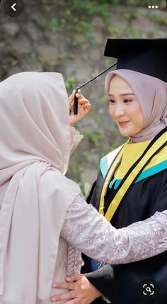 a woman in a hijab is getting her hair combed by another woman