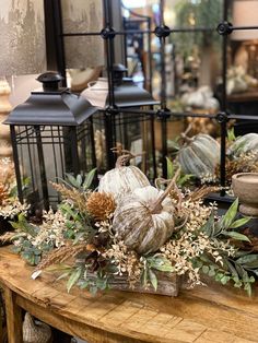 a wooden table topped with lots of different types of pumpkins and greenery on top of it