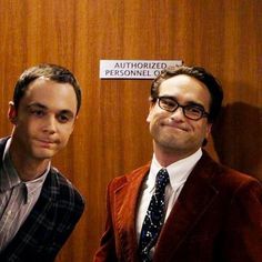 two men standing next to each other in front of a wooden wall with a sign that says authorized personnel only