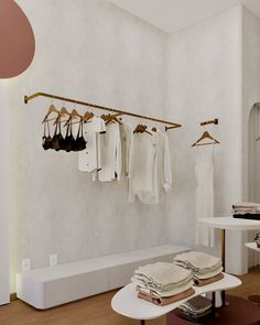 a clothing rack with clothes hanging from it's hooks in a white walled room