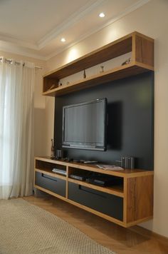 a living room with a large tv on top of a wooden entertainment center next to a window