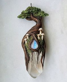 a glass and wood hanging decoration with trees, mushrooms and a tear shaped like a tree