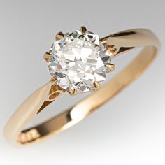 an old mine cut diamond sits in a yellow gold ring