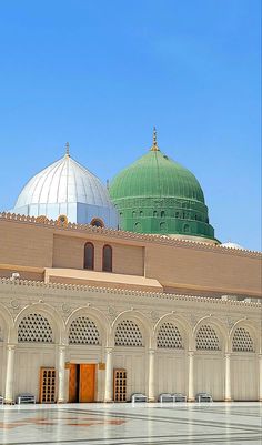 two domes on top of a building with tiled flooring and green dome tops in the background