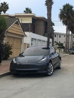 an electric car parked on the side of the road in front of some palm trees