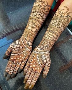 two hands with henna tattoos on them, one is showing the intricate pattern and the other has an elaborate design