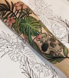 a person with a tattoo on their arm has a skull and flowers in the background