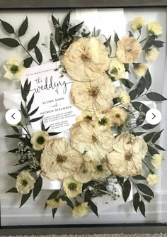 a wedding card and flowers in a frame on the floor next to a sign that reads,