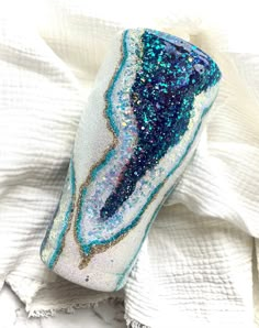 a blue and white vase sitting on top of a cloth covered tablecloth with gold glitters