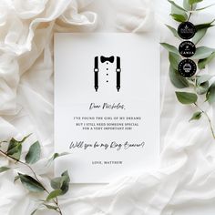 a wedding card with two grooms in tuxedos on it next to some greenery